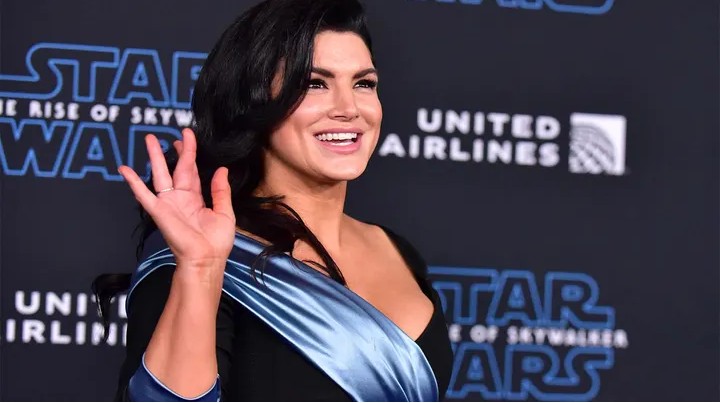 Gina Carano posing on a red carpet in a black gown